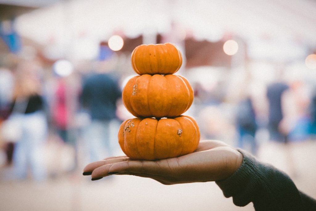 A stack of small pumpkins in someone's hand at a haunted carnival. 