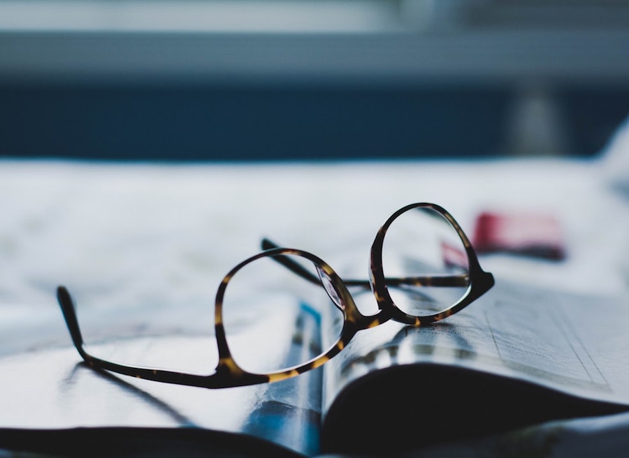 A pair of glasses sitting on a print publication.